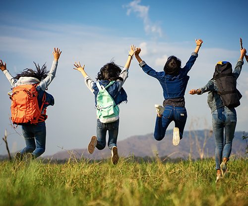 A group of women jump together in the grass field.Beautiful group.